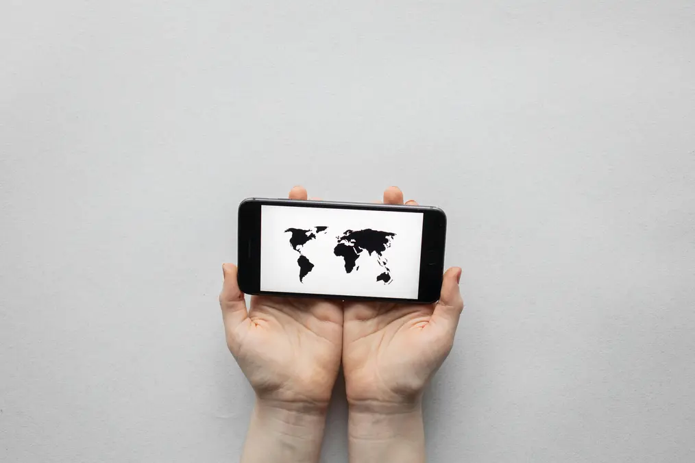 Hands holding a smartphone displaying a world map, symbolizing global connectivity and digital communication.